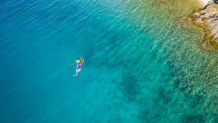 Aerial view of young man riding paddleboard. Paddleboarding is the modern way of transportation and...