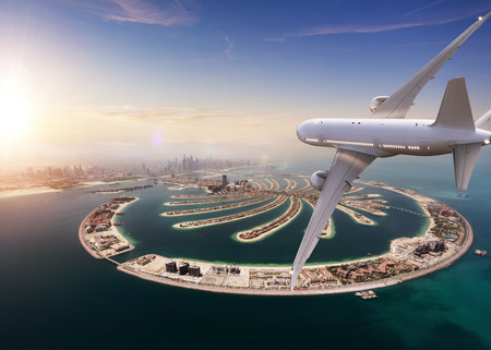 Commercial jet plane flying above Dubai city. Modern and fastest mode of transportation, business life and luxury style of lifeの写真素材