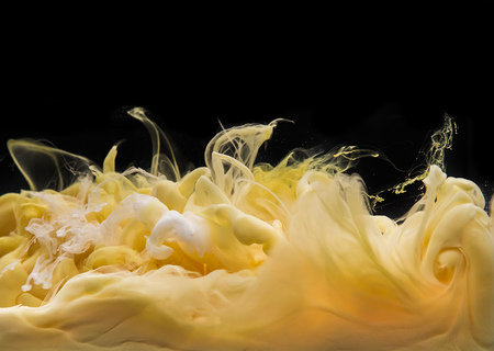 Coloured acrylic ink mixing in water isolated on black background. Abstract art background. Creamy vanilla and caramel mixed togetherの写真素材