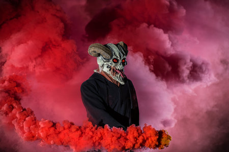 Devil with scary mask surrounded by red smoke. Halloween and horror concept