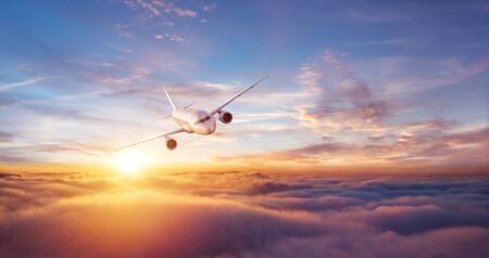 Passengers commercial airplane flying above clouds in sunset light. Concept of fast travel, holidays and business.の写真素材