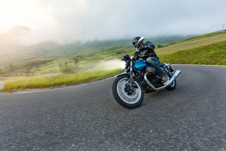Motorcycle driver riding in Alpine landscape. Lifestyle photo with motion blur effect.
