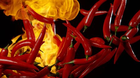 Flying red hot chilli peppers with flames, isolated on black backgroundの写真素材