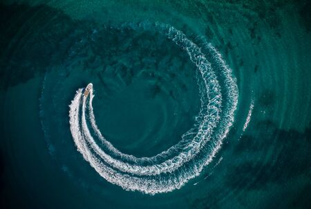 Aerial view of speed motor boat in shallow water, creating wheel shapeの写真素材