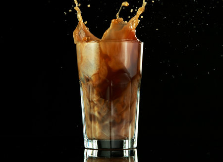Splashing ice coffee drink on black background. Freeze motion of fresh summer drink.の写真素材