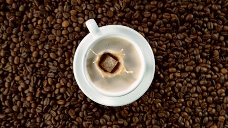 Falling sugar canes into cup of hot coffee, high angle of view. Still life scene made of pile of roasted coffee beans.の写真素材