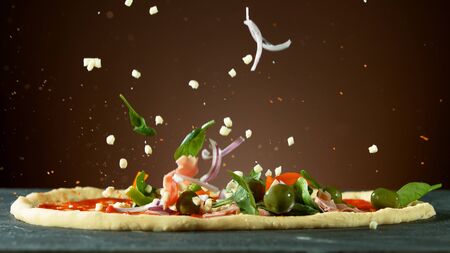 Falling raw ingredients on pizza, freeze motion. Italian traditional meal.の写真素材
