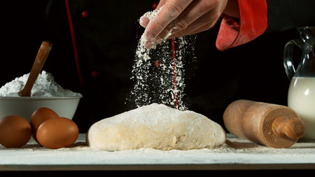 Freeze motion of pouring flour on yeast dough. Food preparation concept, ingredients around