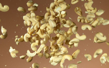 Realistic freeze motion of flying cashews on brown background.