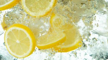 Lemon Slices with ice cubes falling deeply under water isolated on white backgroundの写真素材