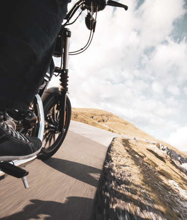 Driver riding motorcycle on an asphalt road in mountain, detail of front wheel, close-up.front,の写真素材