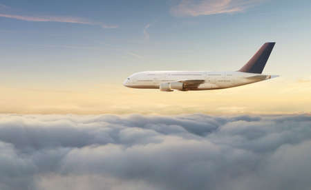 Passengers commercial airplane flying above clouds in sunset light. Concept of fast travel, holidays and business.の写真素材