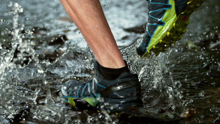Close-up of man feet running in water, freeze motion. Splashing water around.