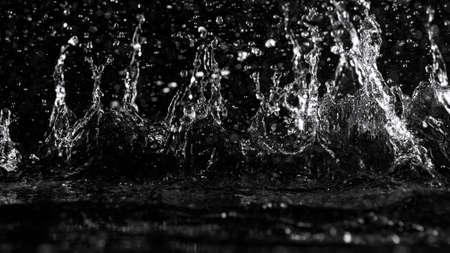 Freeze motion of water splash on black background. Studio shot, space for product placement.の写真素材