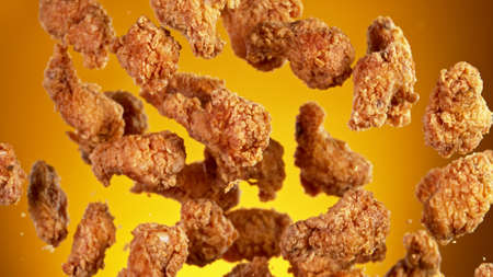 Freeze motion of flying pieces of fried chicken pieces on golden background. Concept of levitating food.の写真素材