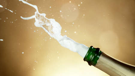 Champagne bottle beying opened. Concept of celebration New Year, birthday or success. Studio shot, freeze motion, bright golden background.の写真素材