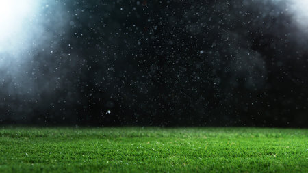 Soccer ball on grass with dark background and lights, placed on center of image.の写真素材