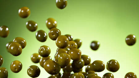 Freeze motion of flying green olives with leaves, isolated on green background.の写真素材