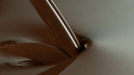 Close-up of pouring stream of melted chocolate, creating curly shapes.の写真素材