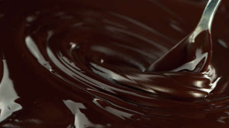 Close-up of pouring stream of melted chocolate, creating curly shapes.の写真素材