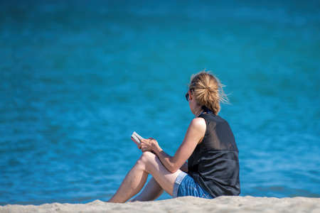 woman reads a book sitting on the beachの写真素材