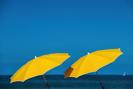 two yellow umbrellas and sea and blue skyの写真素材