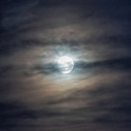full moon behind cloudsの写真素材