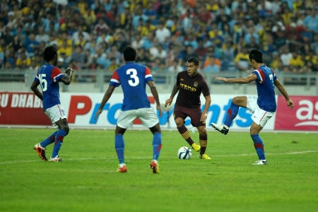 KUALA LUMPUR - JULY 30   Carlos Teves run the ball through Aidil Zafuan 7  and S Subramaniam  3  during Manchester City friendly match against Malaysia at National Stadium, Kuala Lumpur in July 30, 2012  Manchester City won 3-1 のeditorial素材
