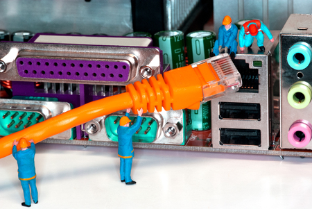 Computer Network Internet Cable - Miniature construction worker figurines posed as if working on a network connection.の写真素材