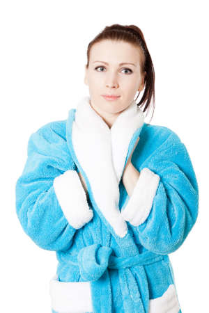 Young attractive woman warms her hand in sky-blue bathrobe isolated on whiteの写真素材