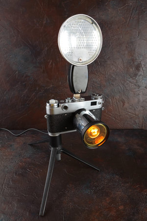 A vintage lamp made from an old film camera on a brown cement background.の写真素材