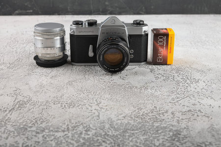 MOSCOW, RUSSIA, JUNE 05, 2018. The old Japan 35 mm SLR camera Asahi Pentax Spotmatik with 55 mm Pentax lens, released 1971 with film packings lford & Kodak on black cement background .のeditorial素材