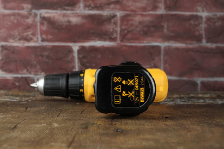 MOSCOW, RUSSIA, AUGUST 21, 2018. 12V Cordless Drill/Drivers DeWalt DW912 on a wooden table against a brick wall.のeditorial素材