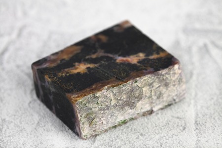 Natural mineral stone - polished charoite gemstone on white cement background.の写真素材