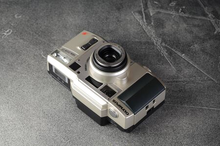The old Japan 35 mm compact film camera Olympus Wiev Zoom 120 with 38-120 mm glass lens, released 2001 on gray cement background.のeditorial素材