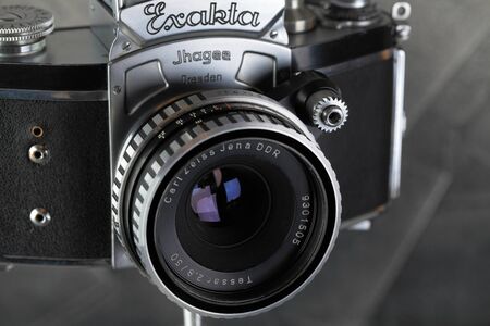 The old German 35 mm SLR film camera Kine Exakta released 1938, with Carl Zeiss lens Tessar 2,8 50, released 1974, on a gray cement background.のeditorial素材