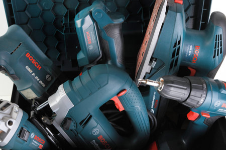 Bosch electric hand tools in a plastic tool box on a white cement background. Grinder, puncher,...