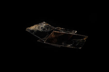 Natural mineral from geological collection - rough muscovite mica, common mica on black glass background.の写真素材