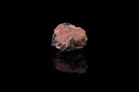 Natural mineral rock specimen - rough rhodonite stone from M. Sidelnikovo, Ural, Russia on black glass background.の写真素材