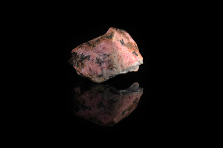 Natural mineral rock specimen - rough rhodonite stone from M. Sidelnikovo, Ural, Russia on black glass background.の写真素材