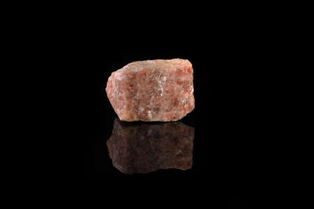 Natural mineral rock specimen - pink marble from Slyudyanka, Baikal, Russia on black glass background.の写真素材
