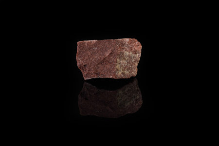 Natural mineral from geological collection - raw pink quartzite stone from Shoksha, Karelia, Russia on black glass background.の写真素材