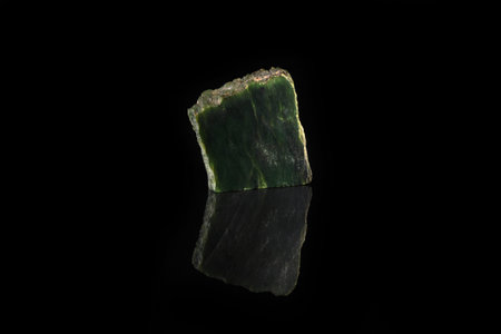 Texture of natural green stone Nephritis on black glass background. Semi precious stones.