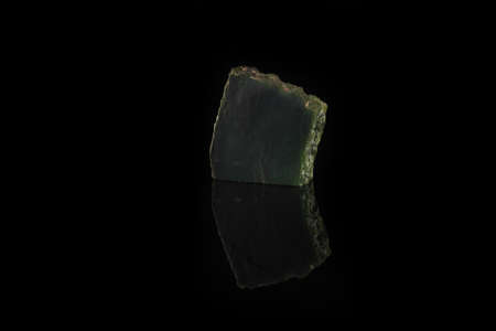 Texture of natural green stone Nephritis on black glass background. Semi precious stones.の写真素材