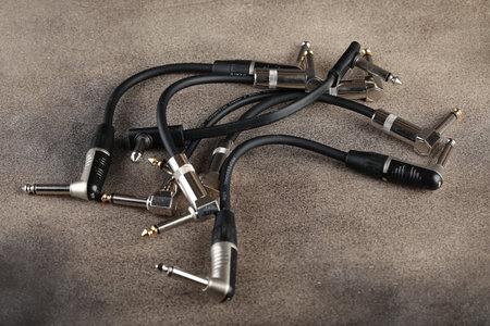 Patches for connecting various pedal sound effects for electric guitars on a brown cement...