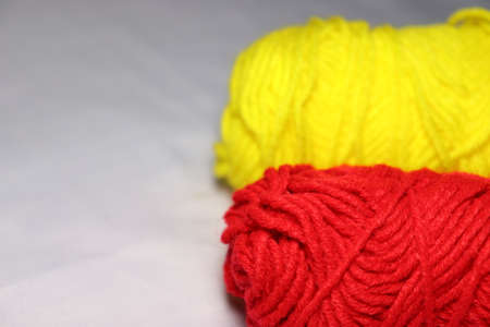 red and yellow colored yarn closeup on white backgroundの写真素材
