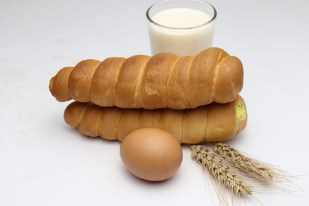 cream roll and ripe wheat and egg and milk on white background