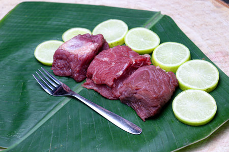 fresh tasty cow beef with sliced lemon and spoon on banana leaf