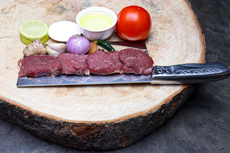 cow beef with spice and sliced lemon and tomato on chopping board