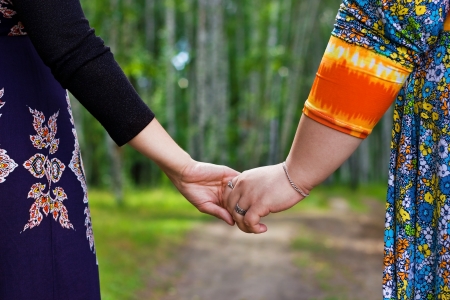 Couple of girlfriens holding by the hands, walking in the forestの写真素材